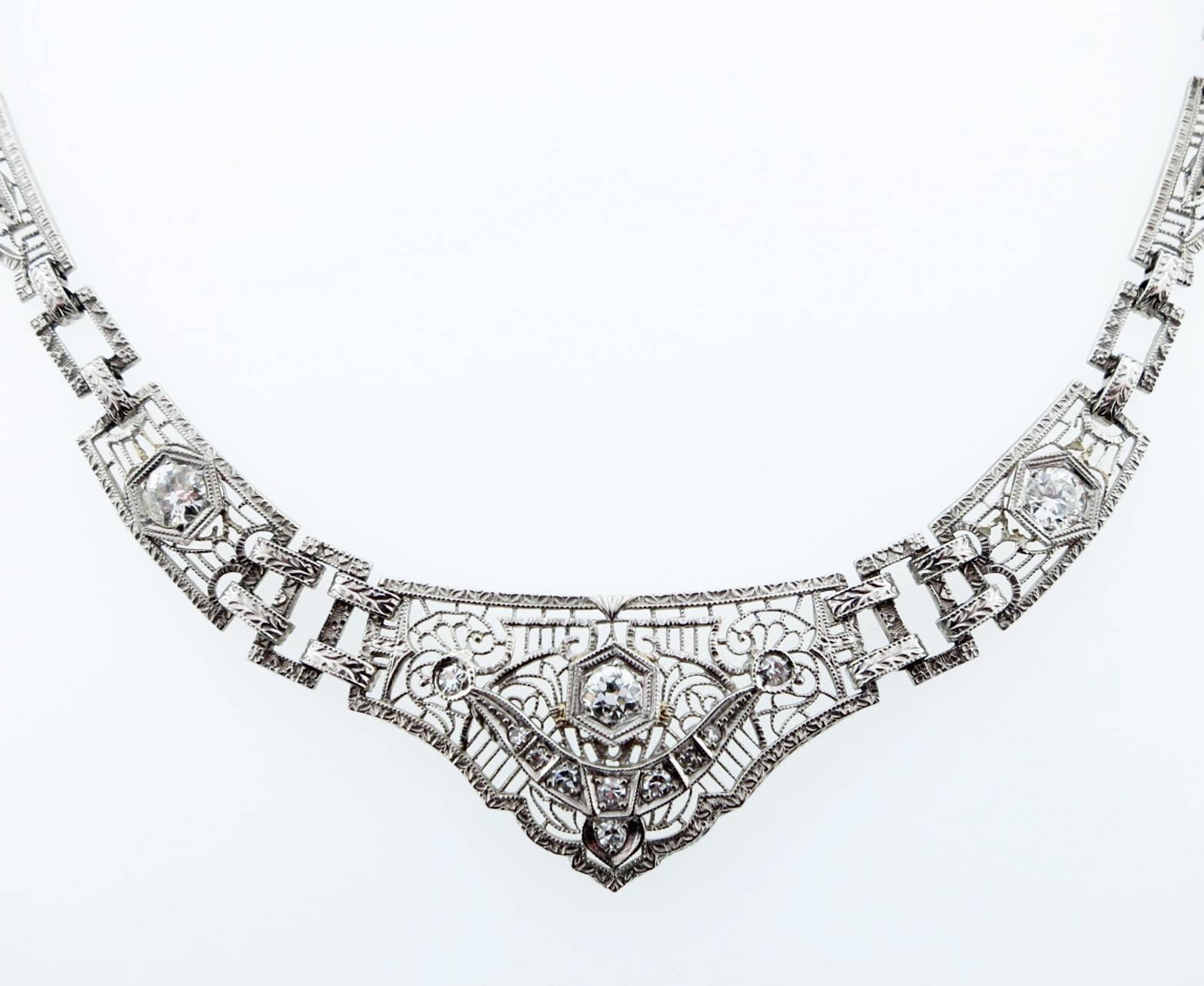 Pretty open filigree necklace in platinum and 14kt. white gold measuring 16 inches in length. The front of the necklace is set 13 round old European cut diamonds totaling approx .60cts. Hidden catch. Circa 1925.