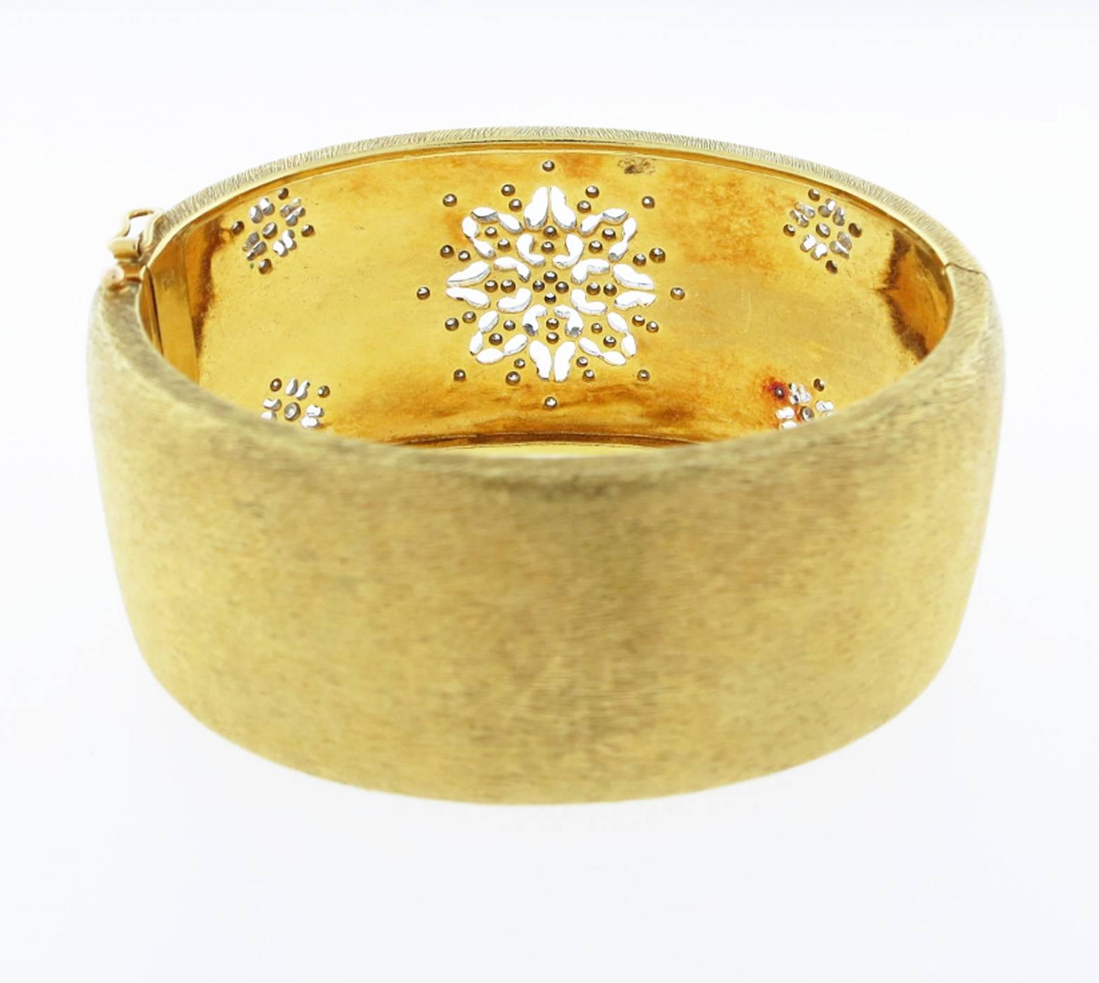 Wide 18kt. yellow gold softly finished slightly tapering to the back bangle bracelet. The bracelet measures approx 1 1/2 inches at the front and is bead set in white gold in an open work snowflake design with 64 round brilliant cut diamonds totaling