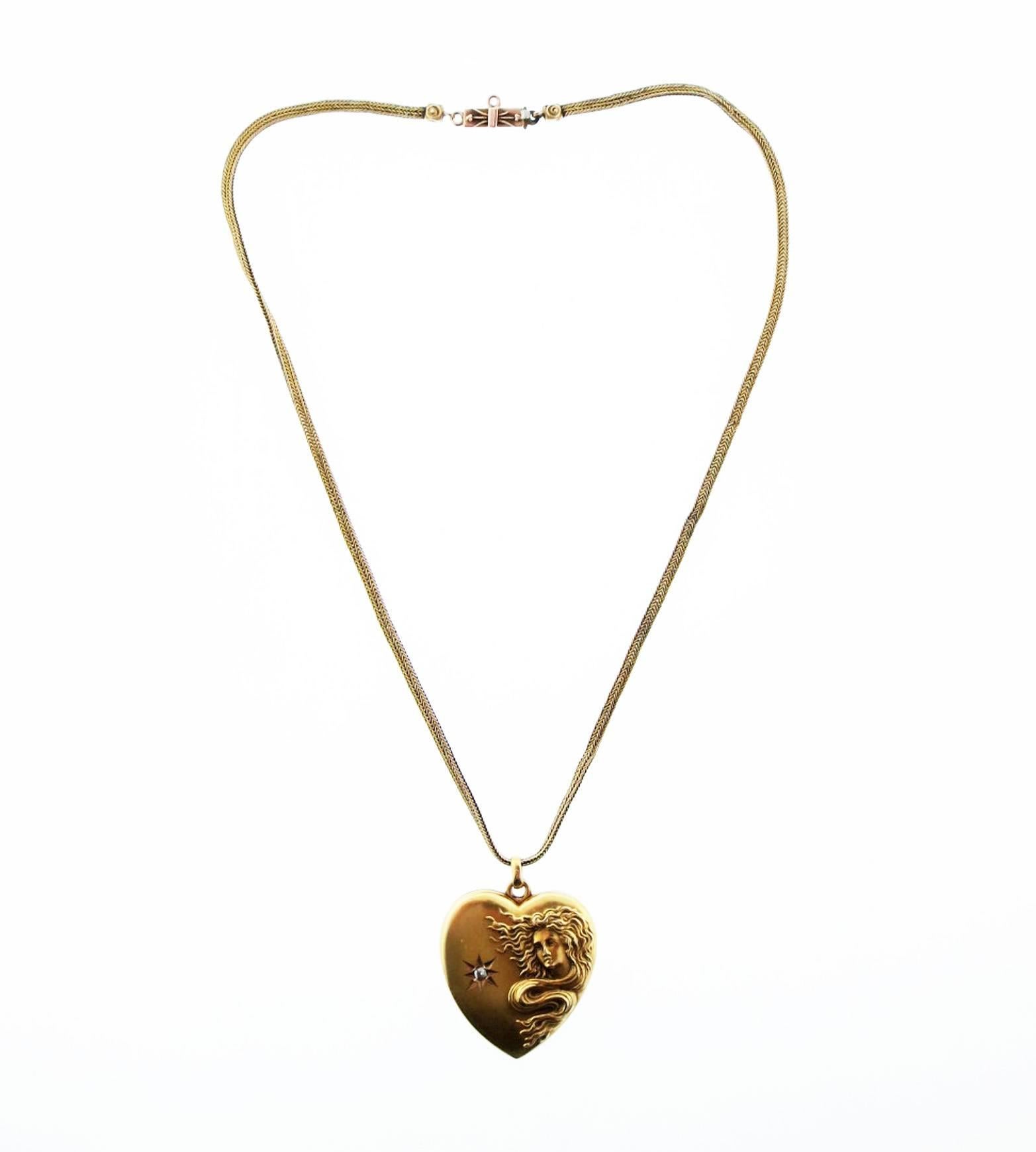 Original patina 14kt. yellow gold Art Nouveau heart shape locket measuring approx 1.25 inches in length with a high relief female form on the front with an accent diamond . The back is engraved with initials. The 14kt. yellow gold antique cable link