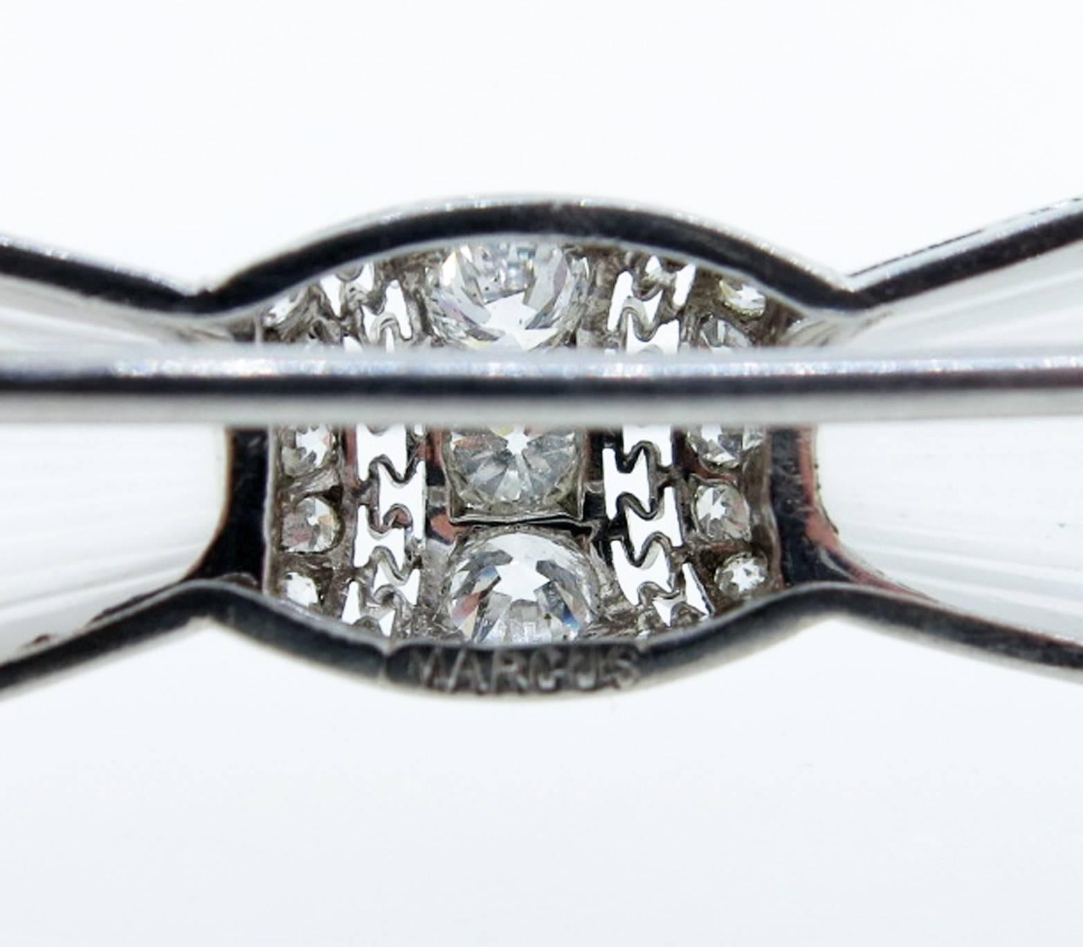 Art Deco carved crystal Marcus bow brooch circa 1925. The brooch measures approx 2 1/4 inches in length. The center is bead set with three old European cut diamonds each weighing approx .15cts. The open work platinum mount is bead set with 50 round