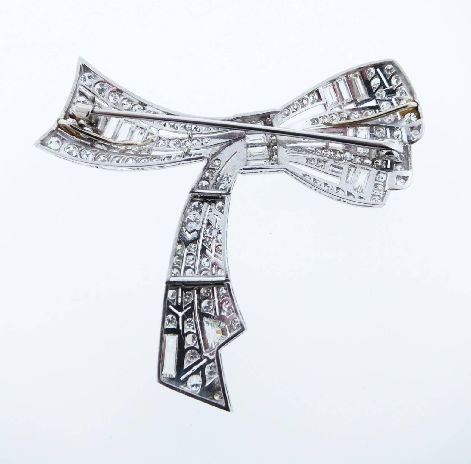Exquisite articulated platinum bow brooch with loops on the back to accommodate a chain attachment . The bow is bead set in a finely mill- grained mount with 17 baguette cut diamonds, 89 round European cut diamonds and one kite cut . Total diamond
