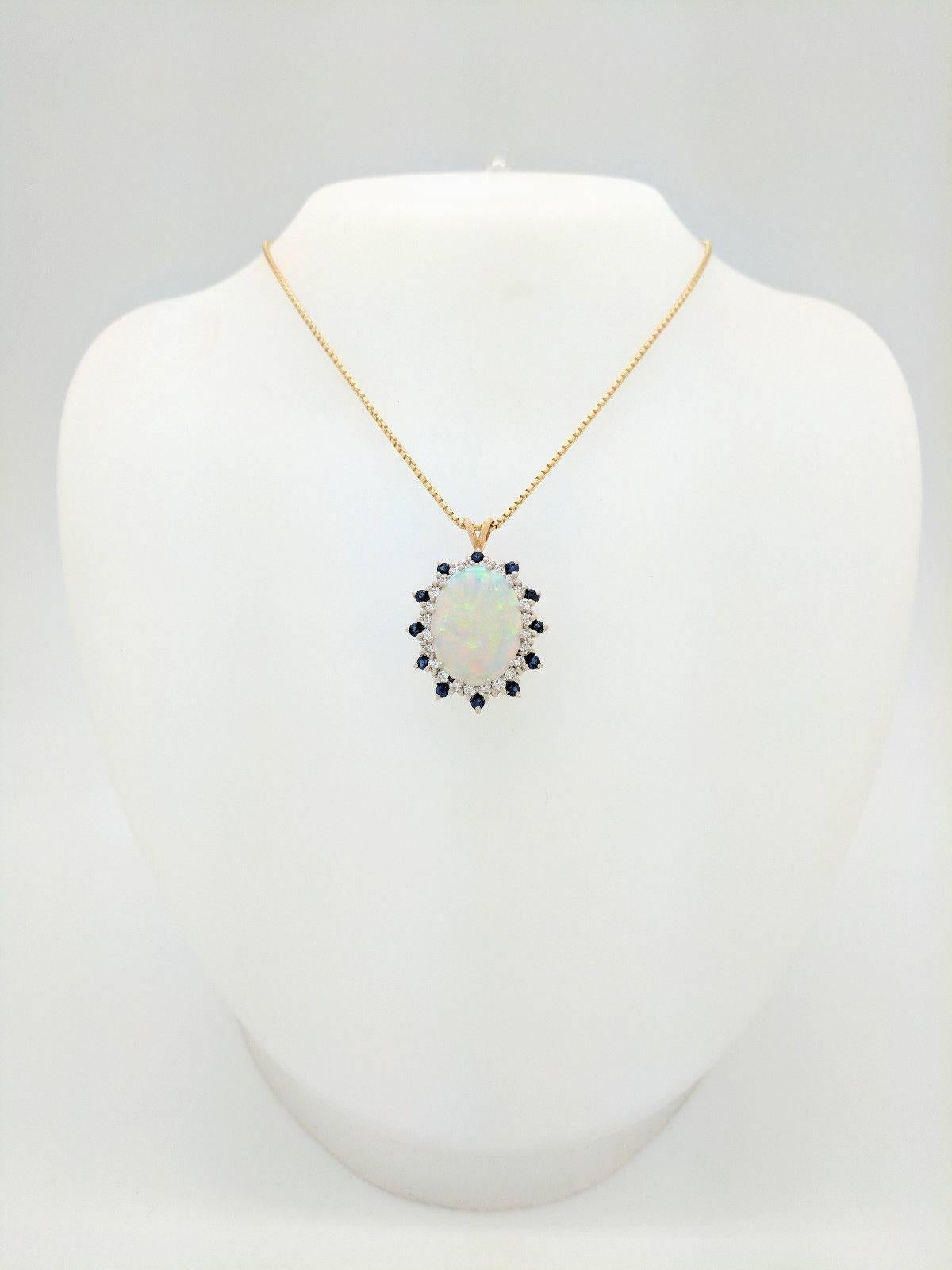 You are viewing a stunning Ladies Estate Australian Opal, Sapphire and Diamond Pendant Necklace. This pendant necklace is crafted from 14k yellow gold and weighs 14.6 grams. It features one 20.5mm x 15.5mm oval shaped Australian opal, twelve .10ct