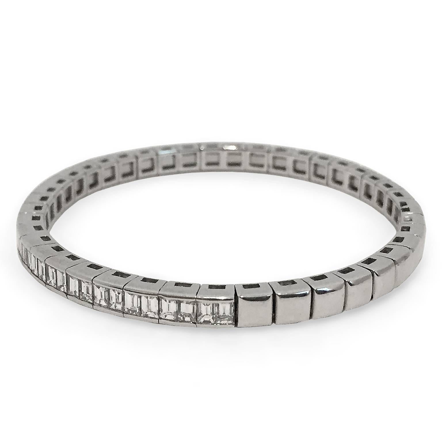 A distinctive modern design showcases approximately 5.50 carats of F-G color VS-VS1 grade baguette-cut diamonds. Diamonds go almost 3/4 of the way around the 18k white gold setting. Easy opening clasp, fits most wrists.