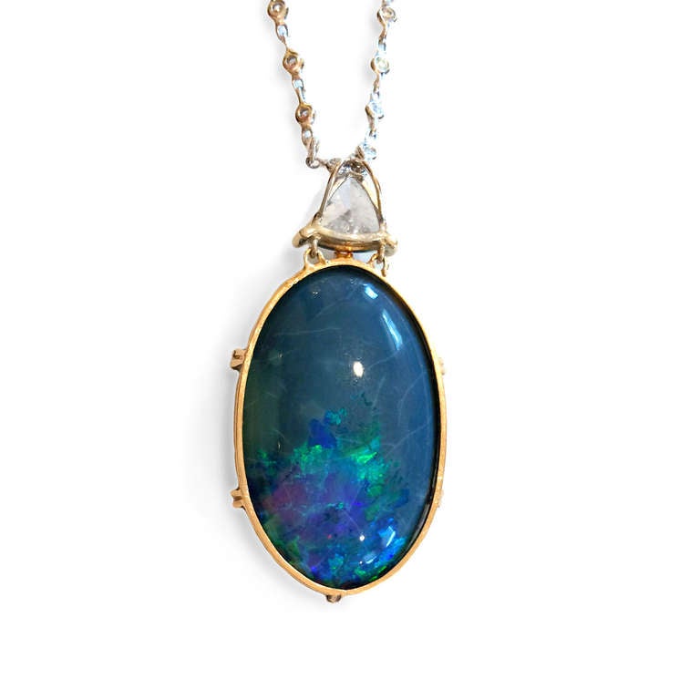 Amazing 25 carat black opal is suspended from a 1.32 carat trillion-cut diamond H color SI, on a 19” 18k white gold and diamond (.68 ct) chain. Lose yourself in the undulating green and blue hues of this stunning piece.