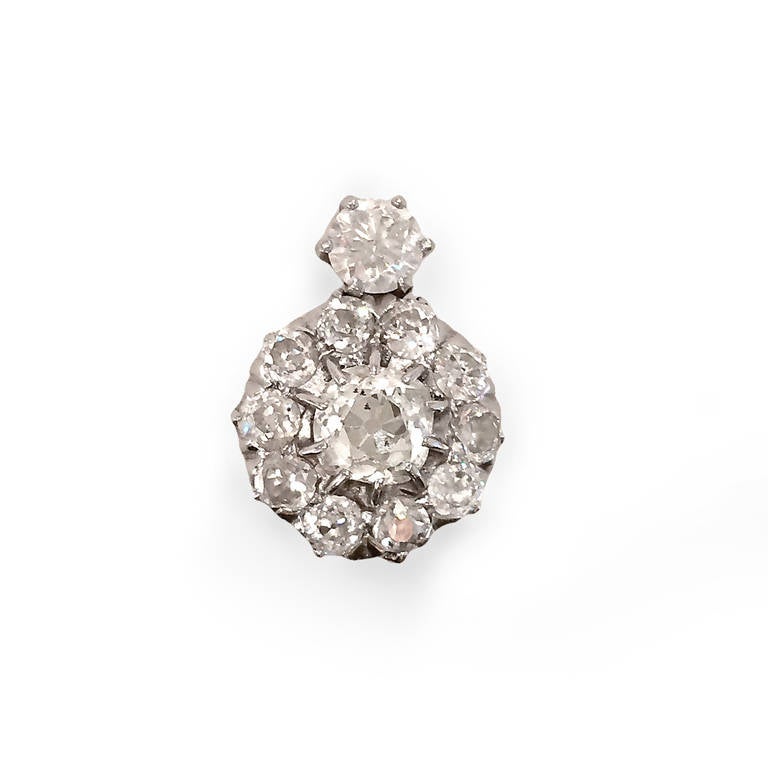 Platinum earrings feature large central old mine-cut diamond surrounded by smaller diamonds.