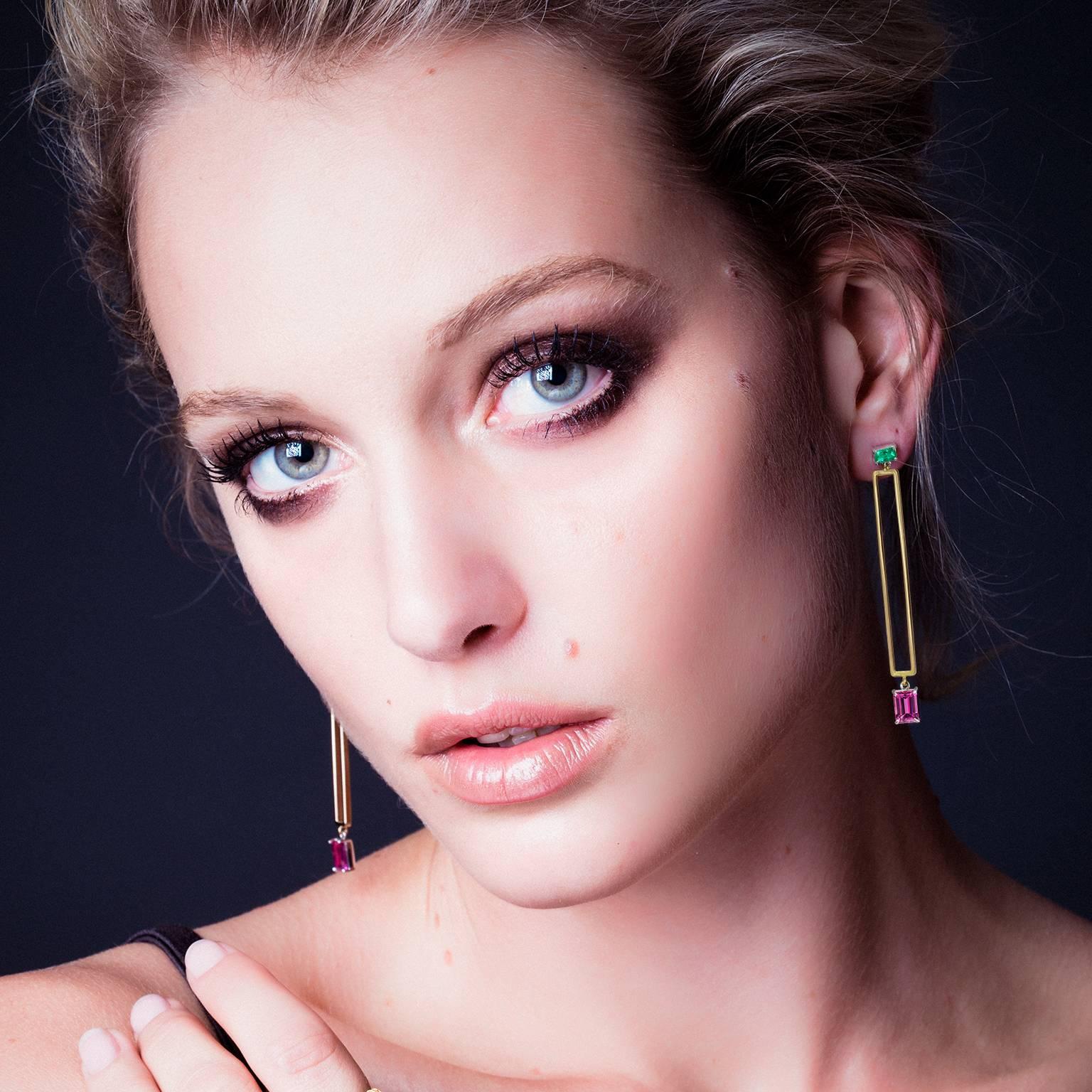 These elegant drop earrings' design was inspired by Manhattan's Art Deco skyscrapers. Handmade in Sydney in 18 karat white and yellow gold and featuring bright, clear Colombian emeralds and pink spinels, these stunning earrings are elegant and