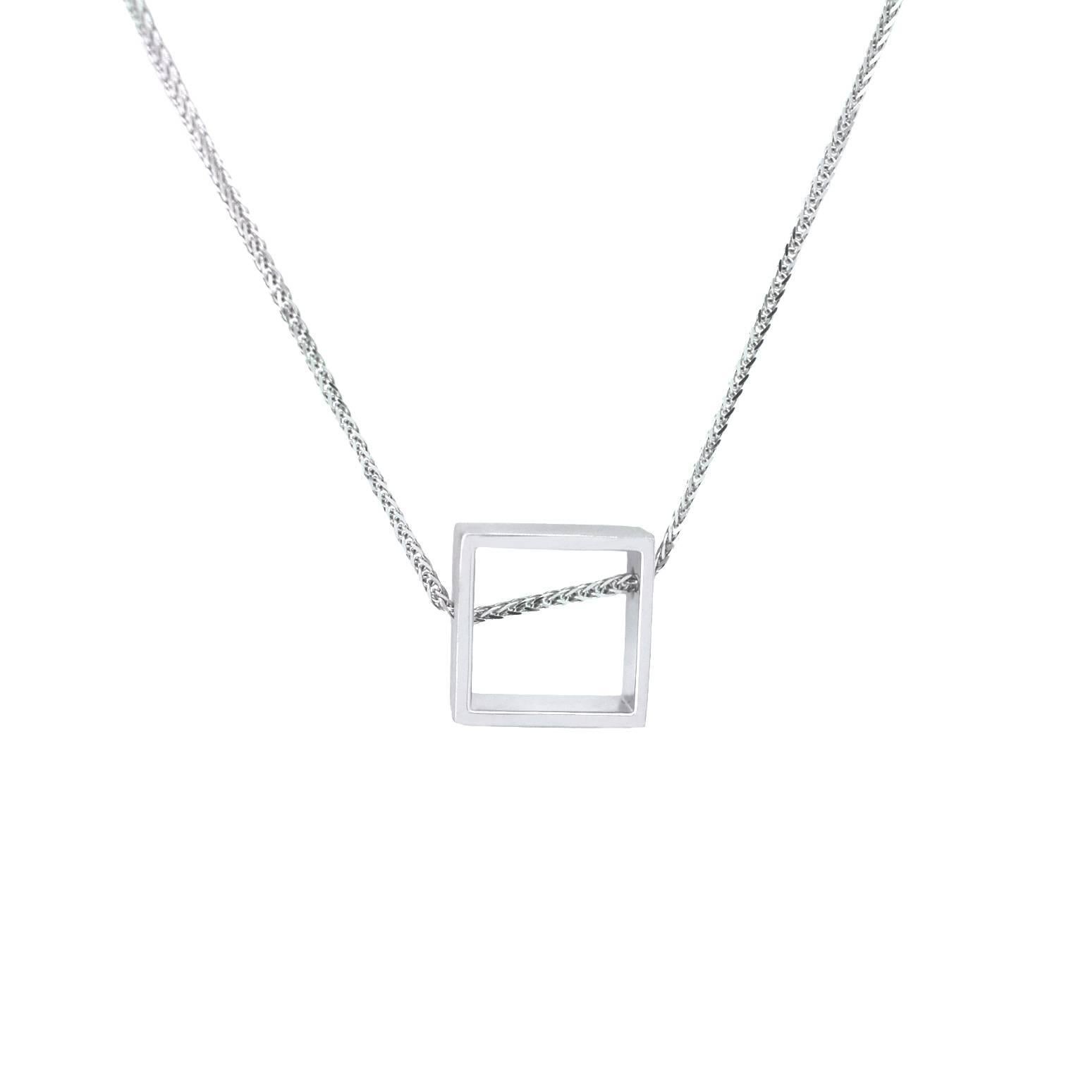 This minimalist geometric pendant sits slightly off-centre, creating a playful effect, and expressing the idea of non-conformity within the boundaries of conformity. The pendant's design utilises negative space, transforming it into a miniature