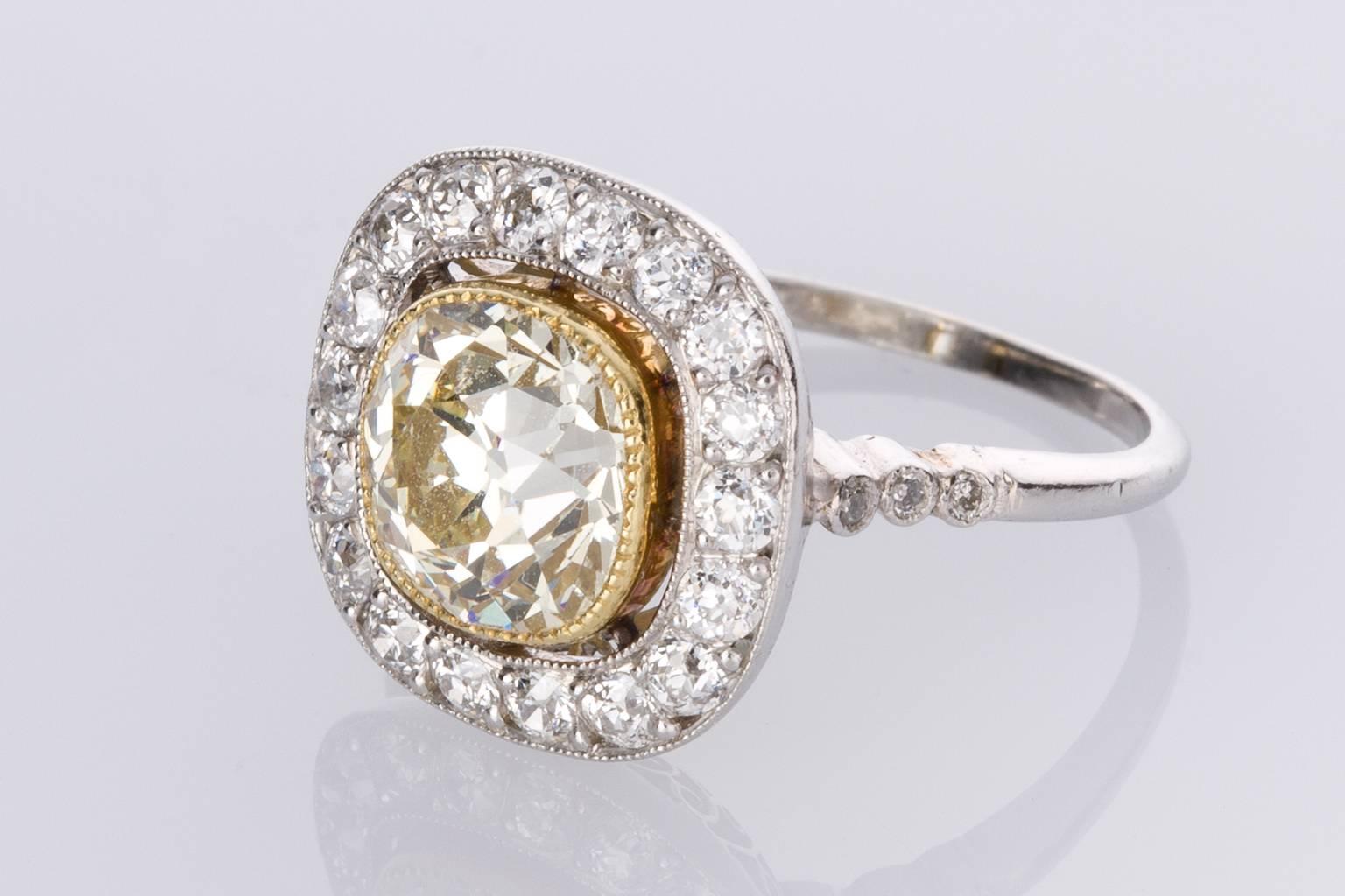 A stunning Art Deco style engagement ring featuring one central old cut fancy light yellow coloured diamond weighing approximately 1.83cts mounted within a fine millegrain floating frame of 18k yellow gold and surrounded with 23 round brilliant cut