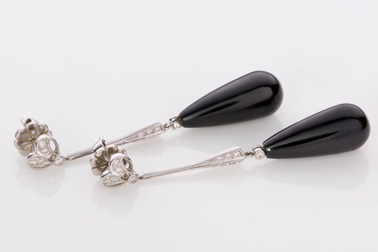 A classic drop earring in the Art Deco style consisting of two long pendalope Onyx drops measuring 20 x 9.2mm with a high polish lustre suspended from 18k white gold diamond bars and filigree piercings with milligrain detailing. Set with a total of