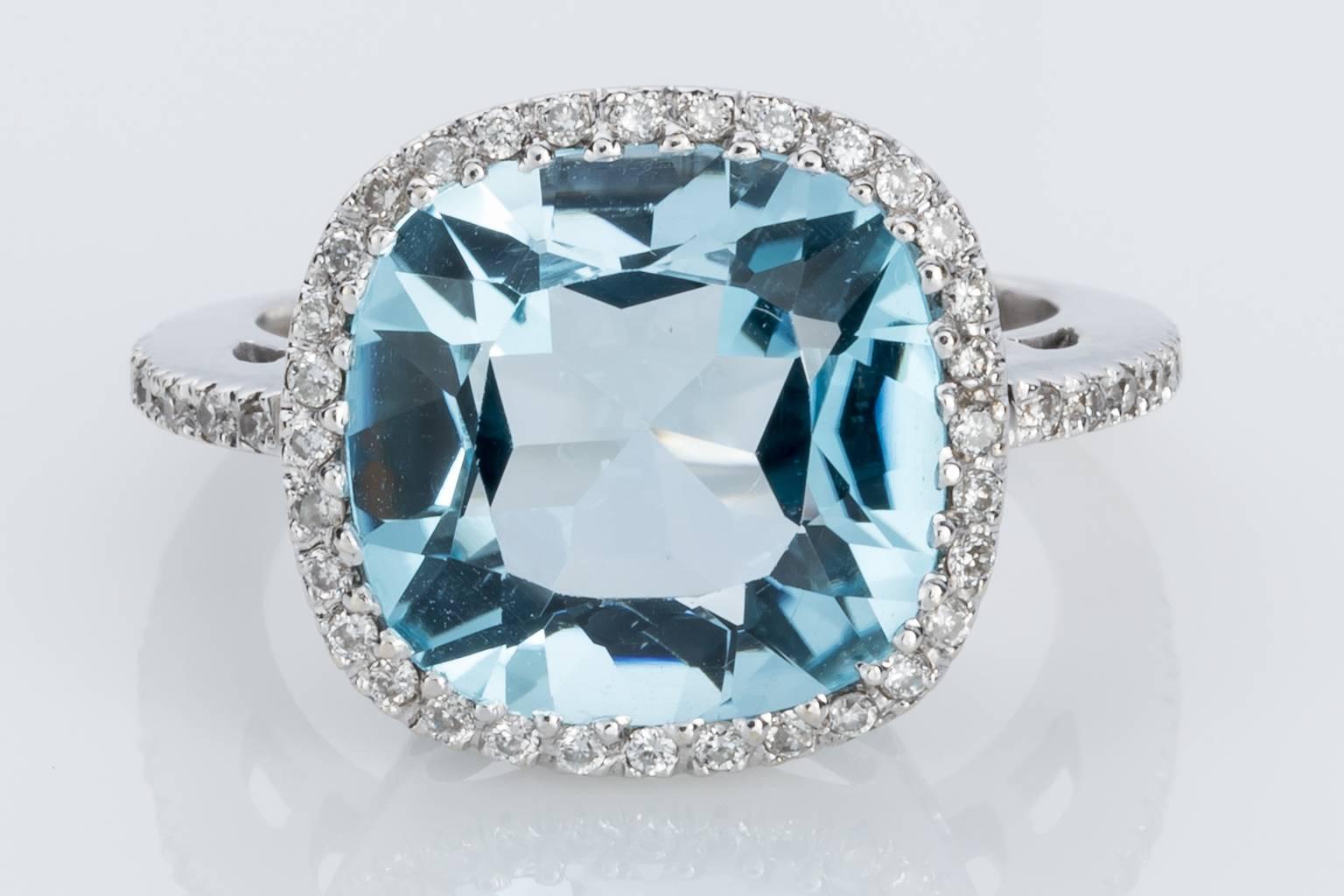 One 18k white gold cushion shape finely made Sky Blue Topaz & Diamond halo style dress ring consisting of a strong mid blue natural topaz, a good bright stone with lots of life and sparkle, calculated at 9.80cts with 32 modern brilliant cut diamonds