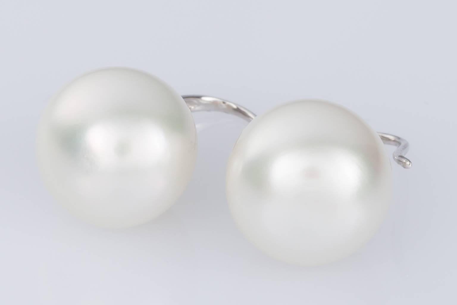 A beautiful pair of South Sea Pearl drop earrings that are elegant and unpretentious. The white bell shaped pearls measure 12.5mm to 12.9mm and are suspended from 18k white gold fluted panels and shepherd hook fittings. 
The pearls have a lovely