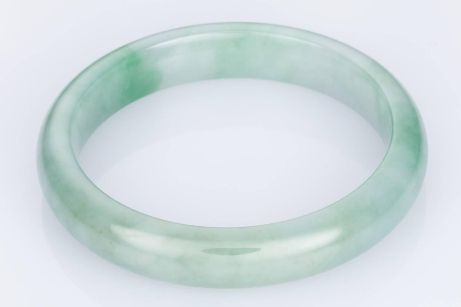 A natural Jade bangle with darker and lighter green tones throughout. 
Size is for a smaller wrist with the inner diameter measuring 5.2cm across. 
Has a heavy feel as the jade is quite dense.
Total weight is approximately 41 grams
