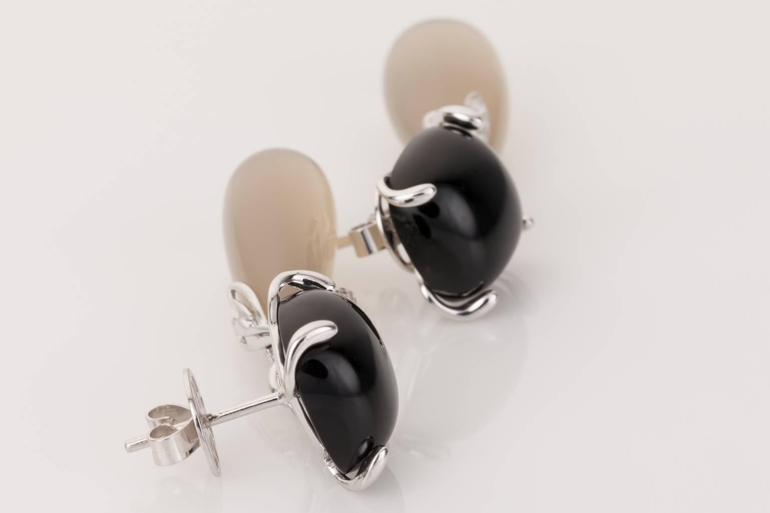 Elegant and sophisticated, these stunning 18k white gold earrings look so superb on the ear. Featuring a cushion cut black onyx cabochon stud set in a four prong setting, with a brilliant cut diamond twist suspending an elongated pear shaped