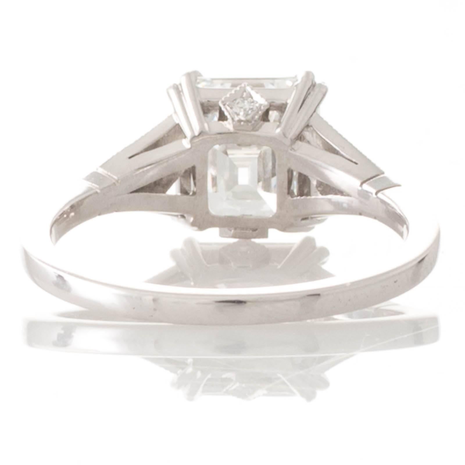 An 18ct white gold Art Deco style ring featuring an impressive 2.23ct Asscher cut diamond accompanied by a GIA certificate stating colour as G clarity VS1 set in four double claws to a railed gallery with pierced detailing grain set with a round