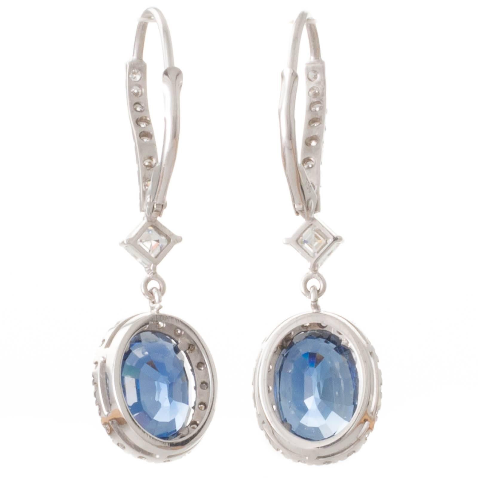 A pair of 18ct white gold hand made earrings featuring oval cut sapphires of 2.77ct and 3.03ct both accompanied by GIA certificates stating they are unheated each set in four claws with a border of 18 (36 in total) round brilliant cut diamonds of