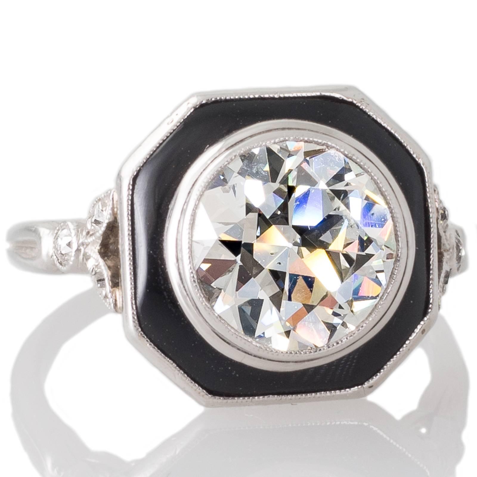 A platinum French Art Deco ring featuring a central 2.20ct transition cut diamond graded as colour J clarity SI1 accompanied by a GIA certificate bezel set within an octagonal piece of onyx which makes up the border above a pierced gallery between a