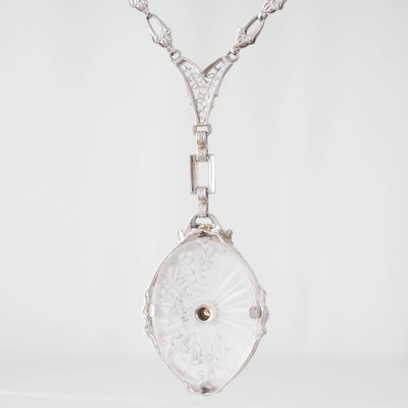 A 14ct white gold Art Deco pendant featuring an oval frosted carved rock crystal plaque grain set to the center with an old cut diamond of estimated 0.03ct, colour J clarity VS, in a box mount. The rock crystal is overlaid to one side with floral