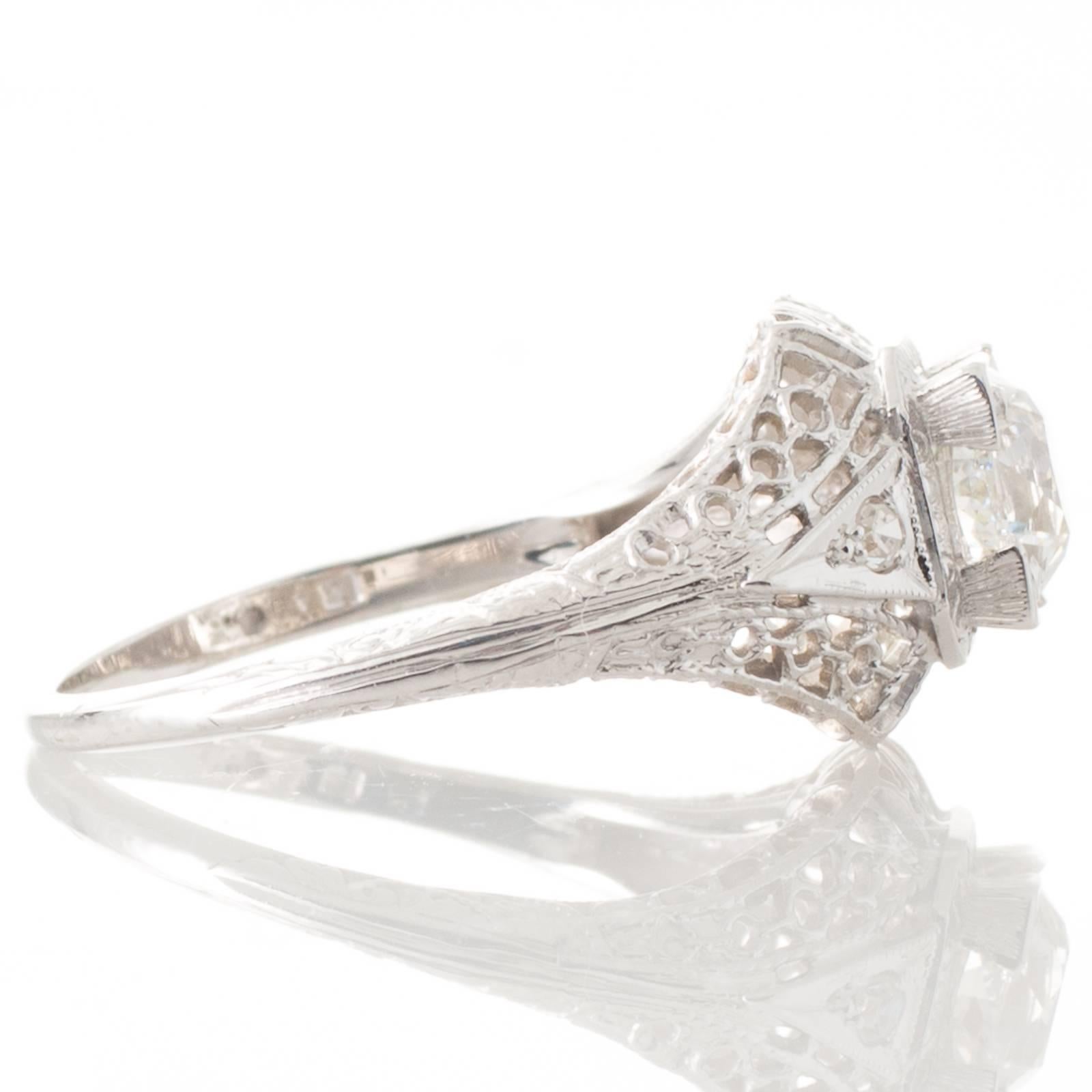 An 18ct white gold ring featuring a solitaire old European cut diamond of estimated weight 0.91ct, graded as colour I-J clarity VS2, bead set within a four corner claw box setting above a fine filigree detailed domed top mount and angled gallery