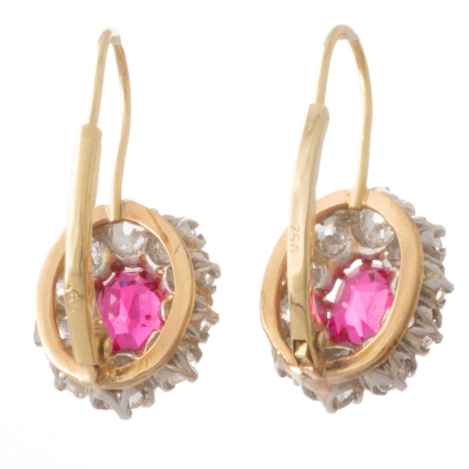A pair of platinum and 18ct yellow gold antique cluster earrings featuring a pair of natural oval faceted spinel of bright pink-red colour of approximate total weight 1.00ct each surrounded by a cluster of old cut diamonds graded as colour J-K
