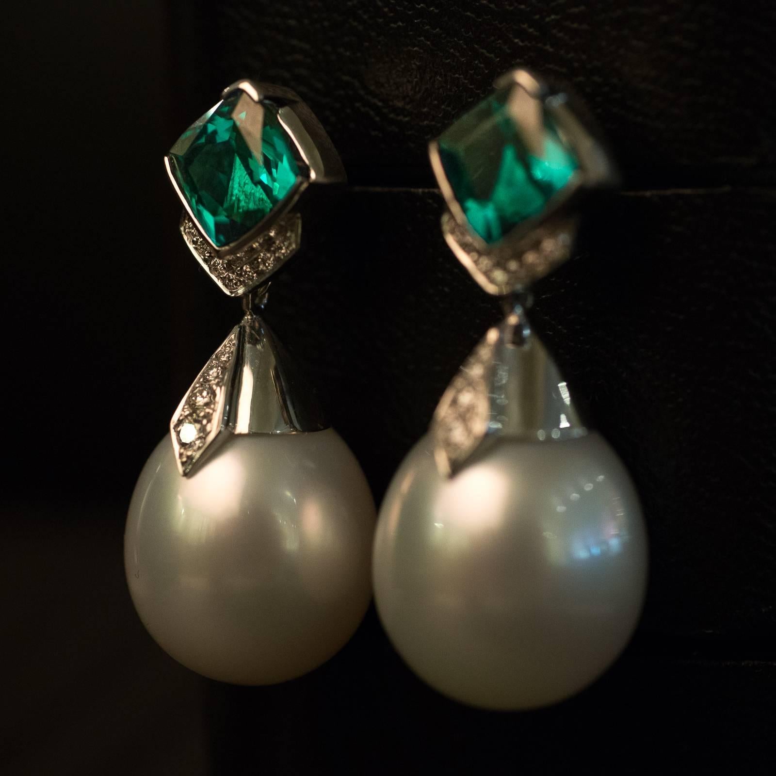 A pair of hand made 18ct white gold Australian South Sea pearl tourmaline and diamond drop earrings. The drop-shaped pearls measure 14mm and have a bright lustre and smooth surface. Set above the pearls to an angle are a pair of half bezel set 6.8mm