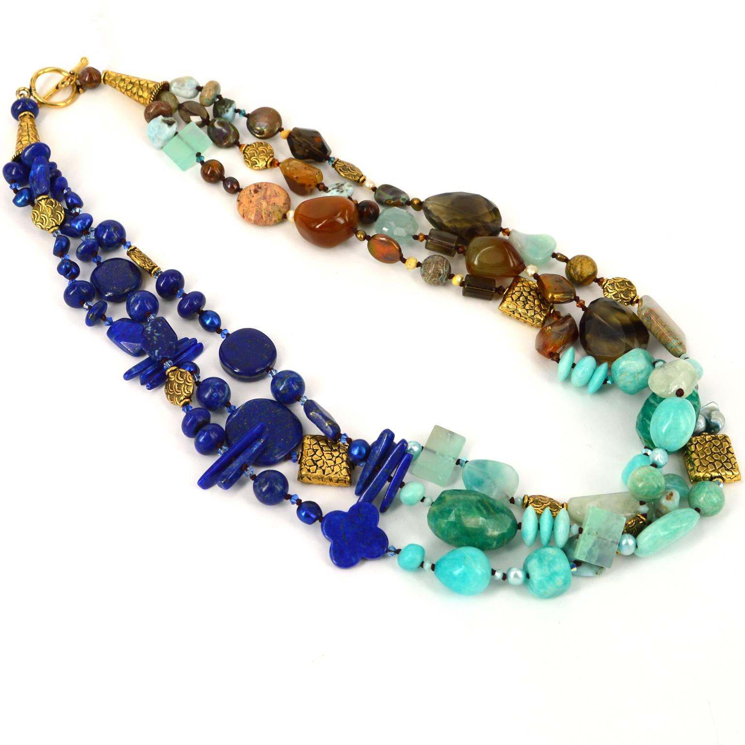 Lapis Dreams- 3 strands of Natural Afghanistan Lapis Lazuli, Amazonite  Peruvian and Russian, Jade, Aquamarine, Larimar  flowing to Smokey quartz, Agate, Jasper with accents in Fresh Water Pearls and Swarovski Beads. 
Clasp and Beads are thick Gold