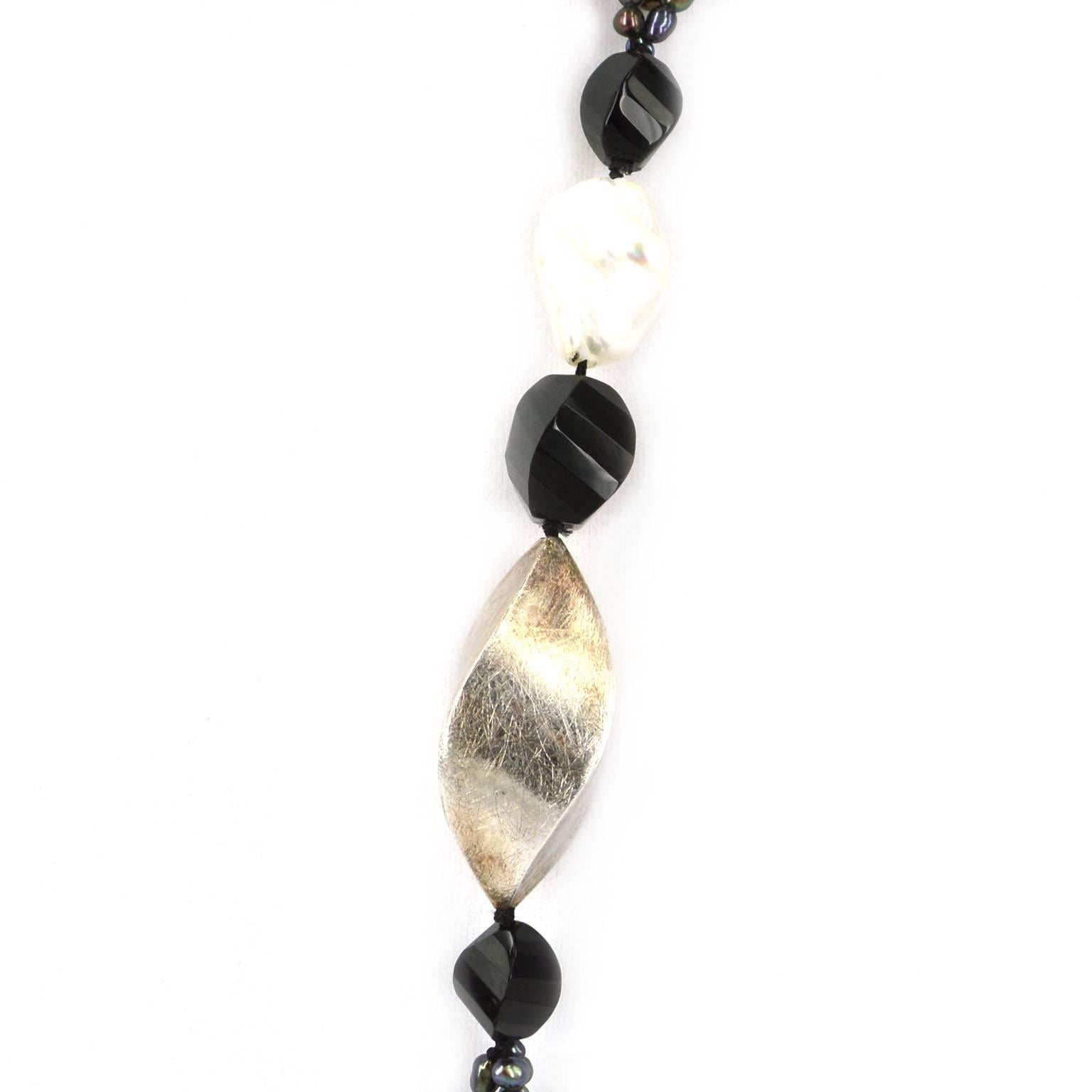 Three strands of mixed size black Freshwater Pearls. With an Onyx, 25mm creamy white Baroque Pearl and Sterling Silver feature using twist olive shapes. Sterling Silver twist olive is 45mm 
Hand knotted on black thread 96cm in length.

