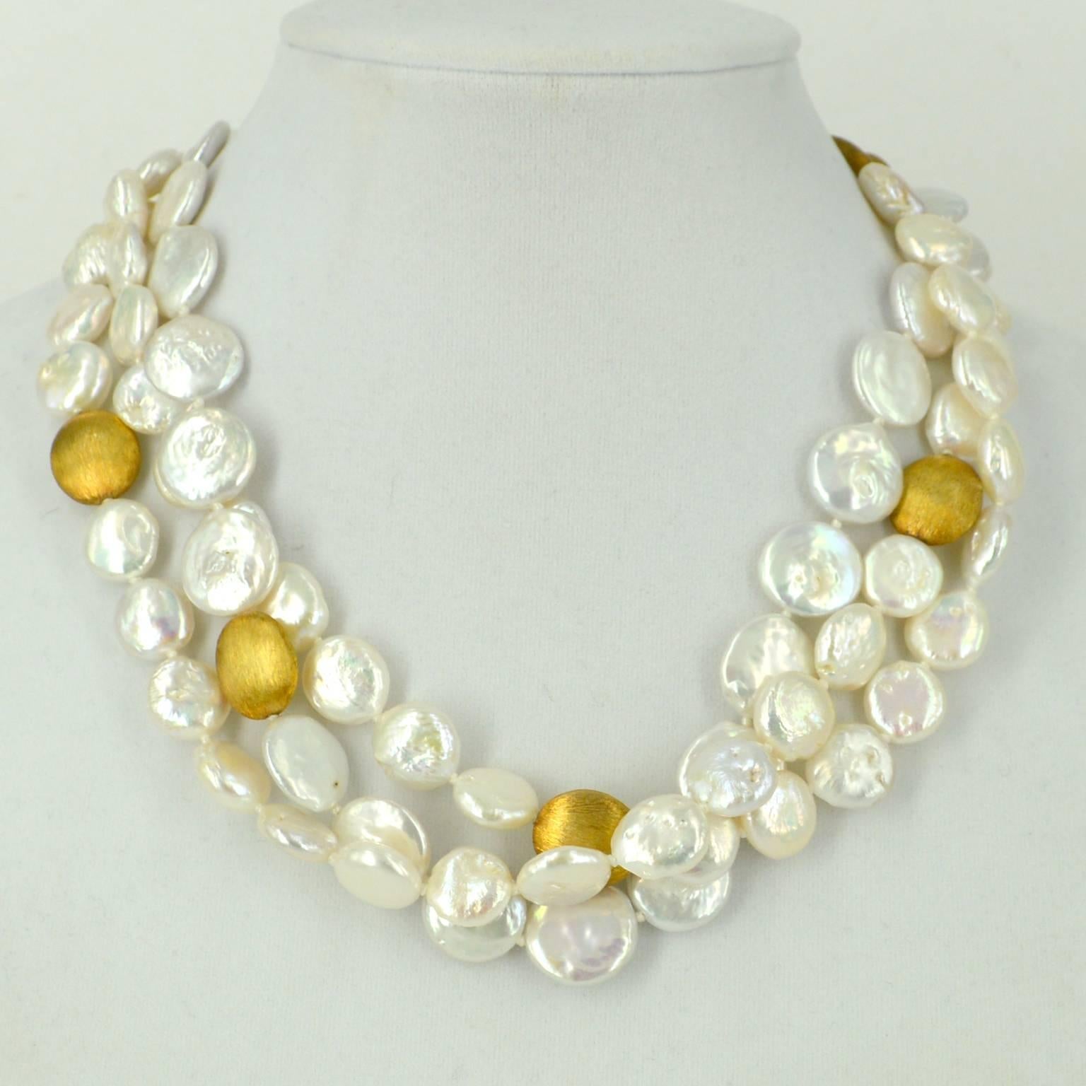 3 strands of Coin Pearls 2 strands are 12mm coin pearls and thrird strand are 15mm. knotted on white thread and spaced with 16x14mm Gold plate Sterling Silver brushed beads and a Gold plate Sterling Silver Magnetic clasp.
finished necklace measures
