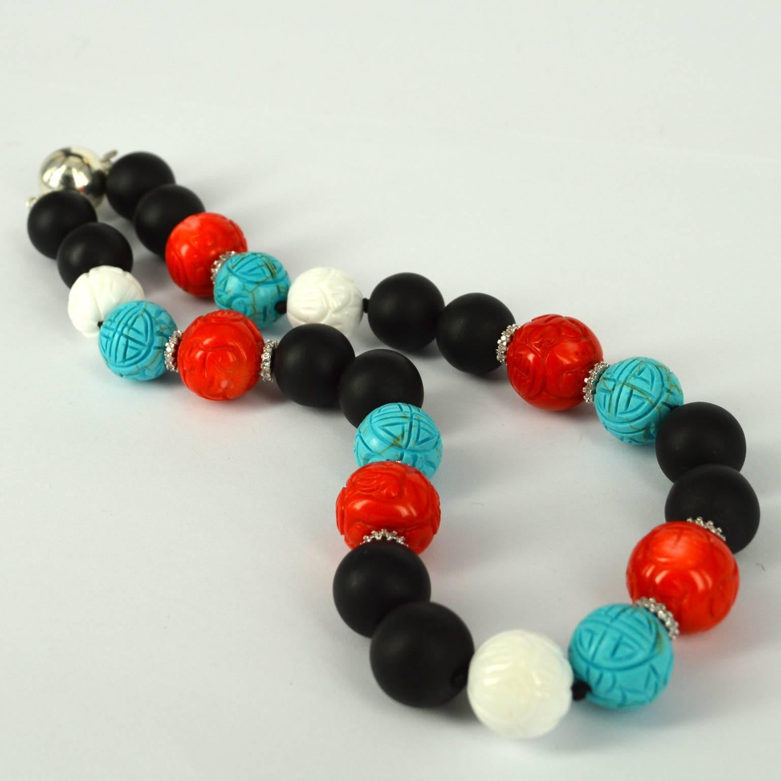 This beautiful necklace features 16mm matt Onyx, carved white Shell, Turquoise Magnasite and carved Orange Sea Bamboo Coral beads. The Orange Coral has Rhodium plate CZ spacers either side andt the necklace is finished with a 16mm Sterling Silver