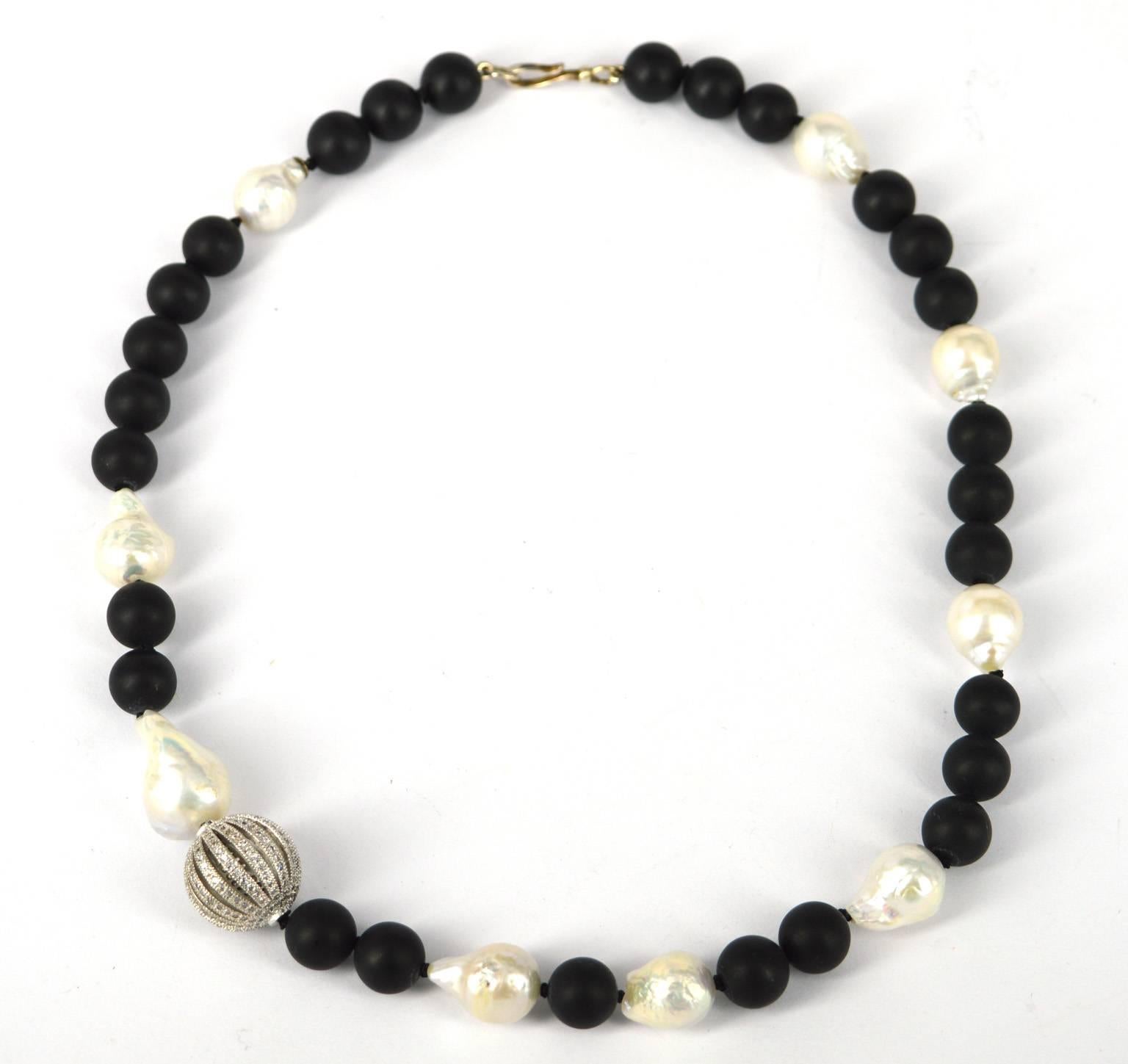 Asymmetrical statement black and white necklace. Matt 10mm black Onyx round and 15mm Fresh water Baroque pearls with a stunning 19cm rhodium plate brass CZ feature bead.

Hand knotted on black thread.
Length of necklace 48cm with Sterling Silver
