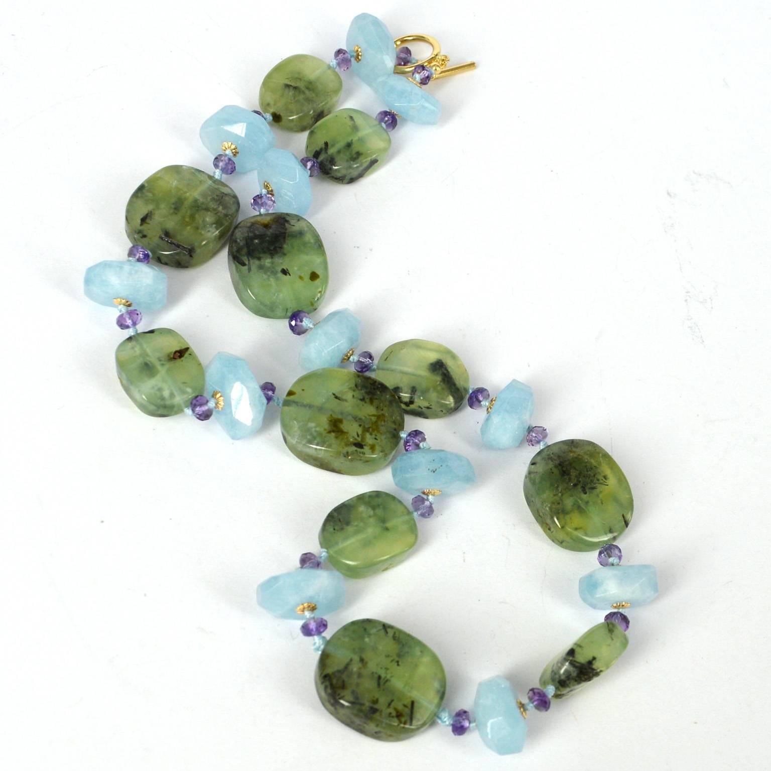 Statement necklace with a mix of polished pillows of Prehnite 20x25mm and 15x19mm spaced with 4x3mm Faceted Amethyst and 8x15mm faceted Aquamarine beads, hand knotted for strength and durability on turquoise coloured thread.  
Finished with a 14mm