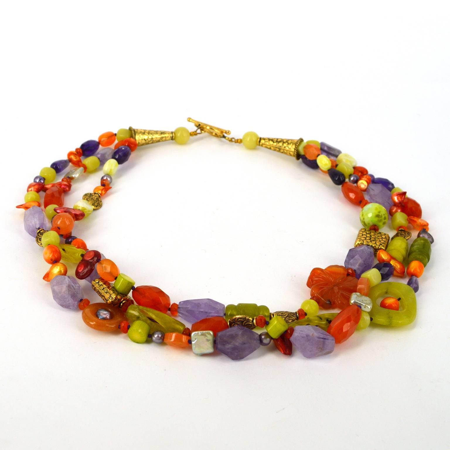 Three strands of an eclectic mix of Amethyst, Carnelian, Jade, Dyed Coral, Freshwater Pearl and Dyed Agate beads. Featuring a gorgeous carved carnelian flower and carved Korean jade. Gold beads and toggle clasp. Hand knotted on amethyst colour
