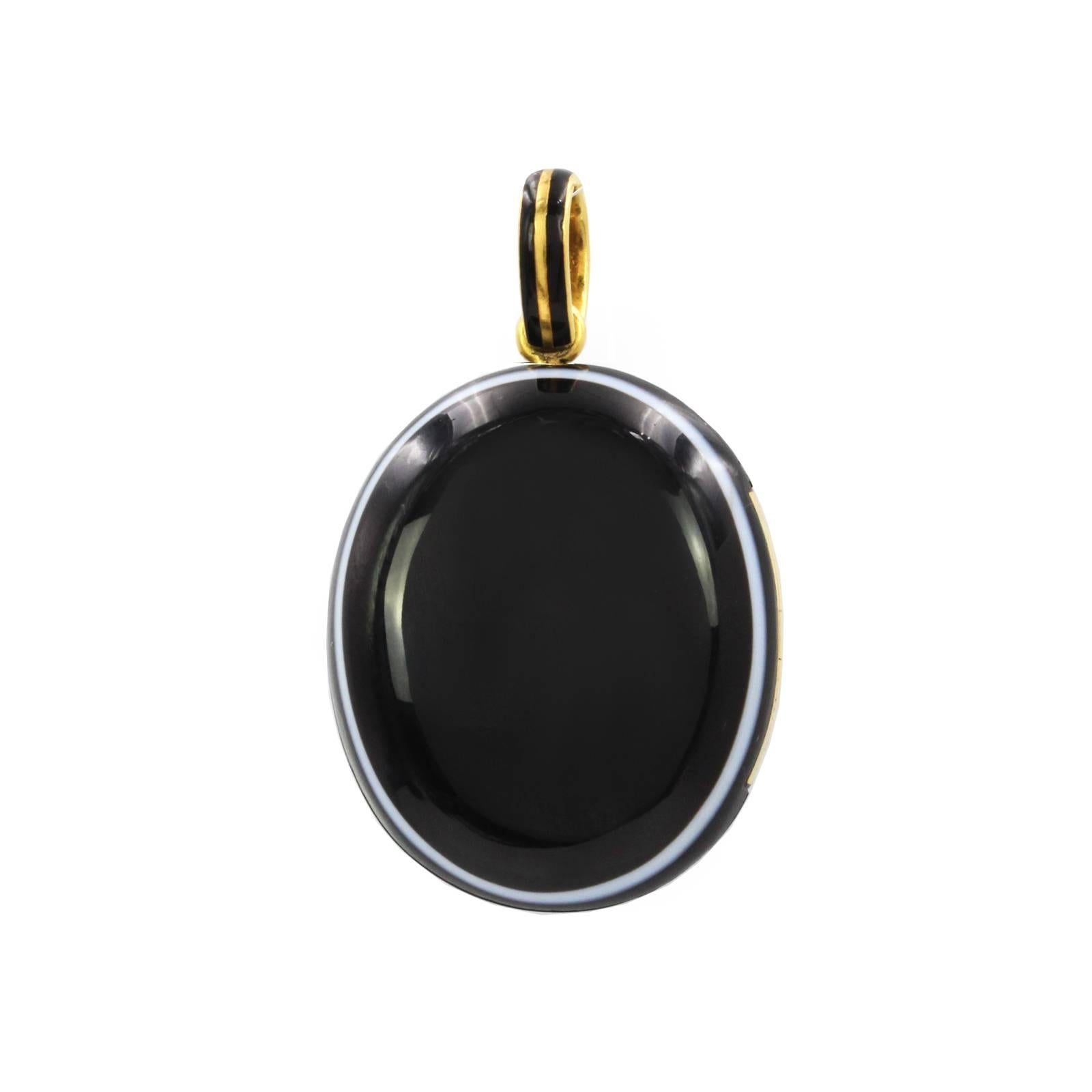 A late Victorian gold banded agate and split pearl locket. The split pearl star, set atop the oval banded agate locket, suspended from a black enamel surmount. Length 4.6cms. Weight 24.2gms.