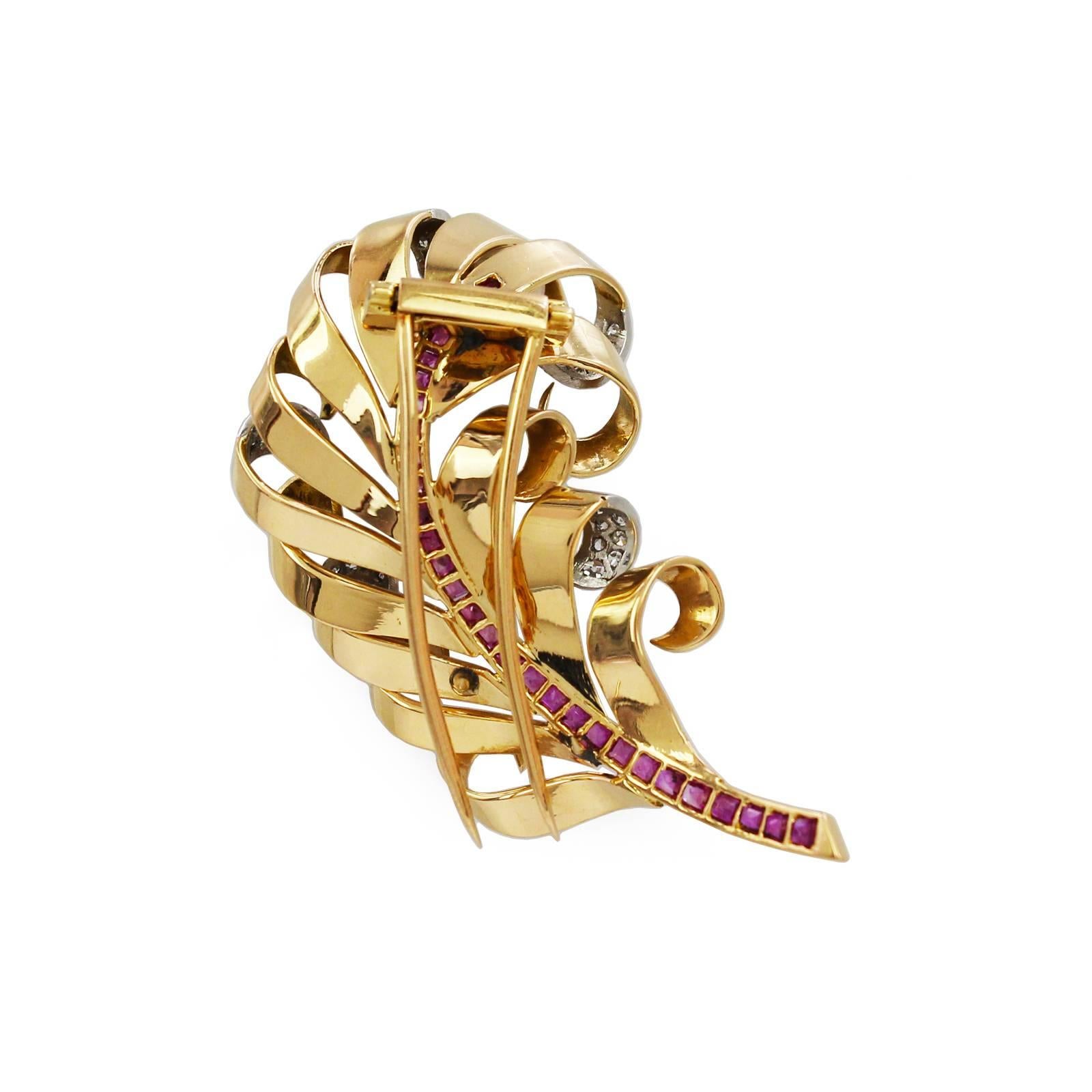 A 1940s' 14k gold ruby and diamond feather brooch. The calibre-cut ruby quill, with single-cut diamond accent scrolling vane. Estimated total diamond weight 0.40ct. Length of brooch 5.2cms. Weight 18.2gms. 