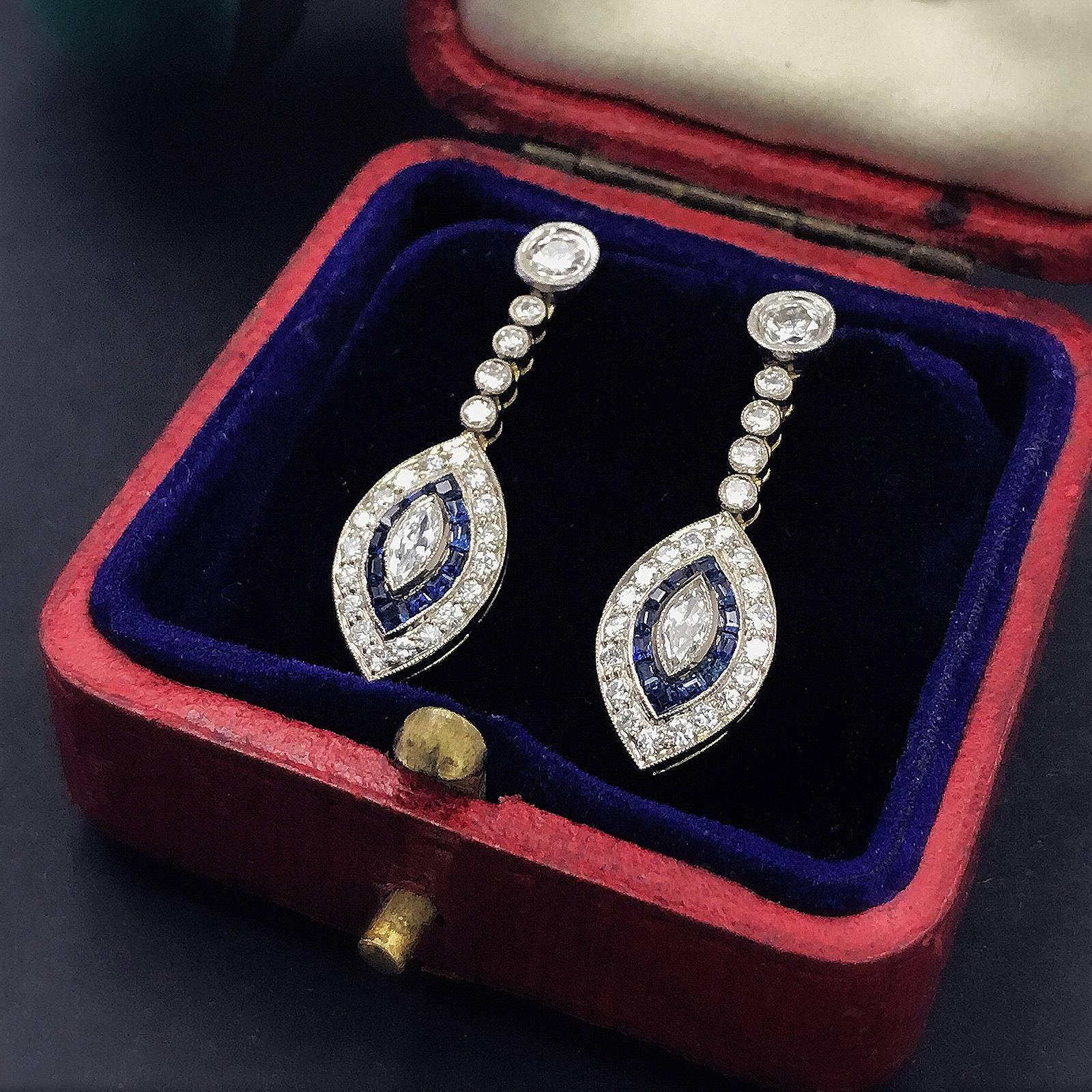 A pair of 1920‘ gold and platinum, blue sapphire and diamond earrings. Design as diamond line with a marque shape drop. Central marque diamond,  accented by fancy-shaped and calibre-cut French-cut sapphires, and outer liner set with round white