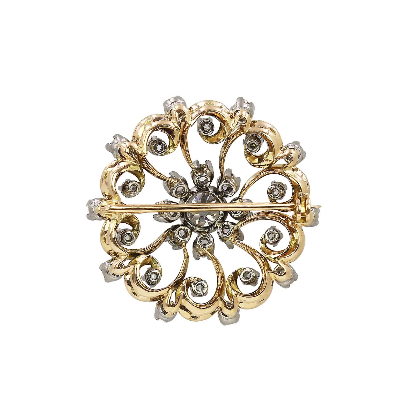 A late 19th century gold diamond brooch. Of bi-colour design, the old-cut diamond, with similarly-cut diamond and scrolling openwork surround. Principal diamond estimated weight 0.70ct, Length 3.3cms. Weight 11.3gms.