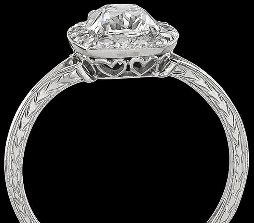 Questo elegante anello di fidanzamento in platino ha al centro uno scintillante diamante certificato GIA con taglio brillante a cuscino che pesa 1,16 carati ed è classificato di colore G e purezza SI2. La pietra centrale è accentuata da splendidi