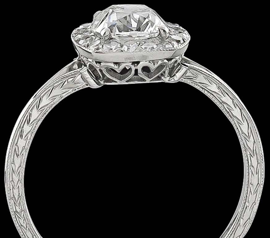 Cette élégante bague de fiançailles en platine est centrée sur un brillant diamant coussin certifié par le GIA, d'un poids de 1,16 ct, de couleur G et de pureté SI2. La pierre centrale est accentuée par des diamants éblouissants de taille ronde