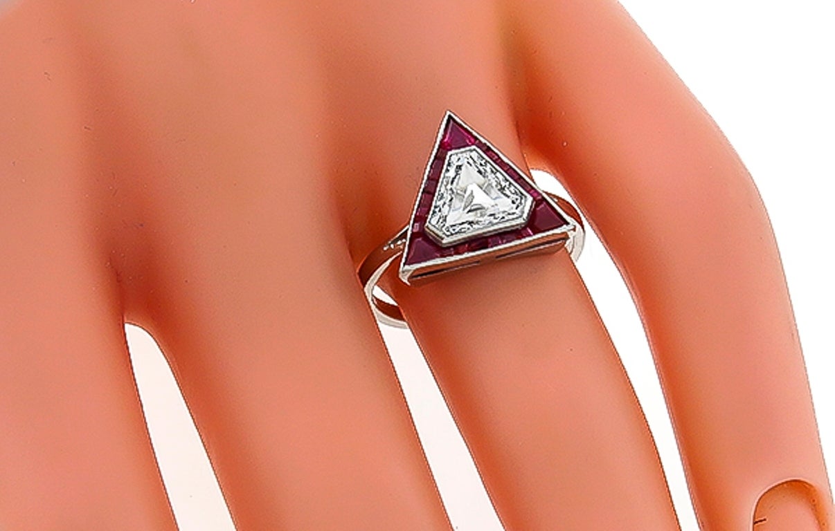 Inspired by the Art Deco era, this platinum ring centers a sparkling EGL certified shield cut diamond that weighs 1.17ct. and is graded  F-G color with SI1 clarity. The center diamond is accentuated by lovely faceted and shield cut rubies that weigh