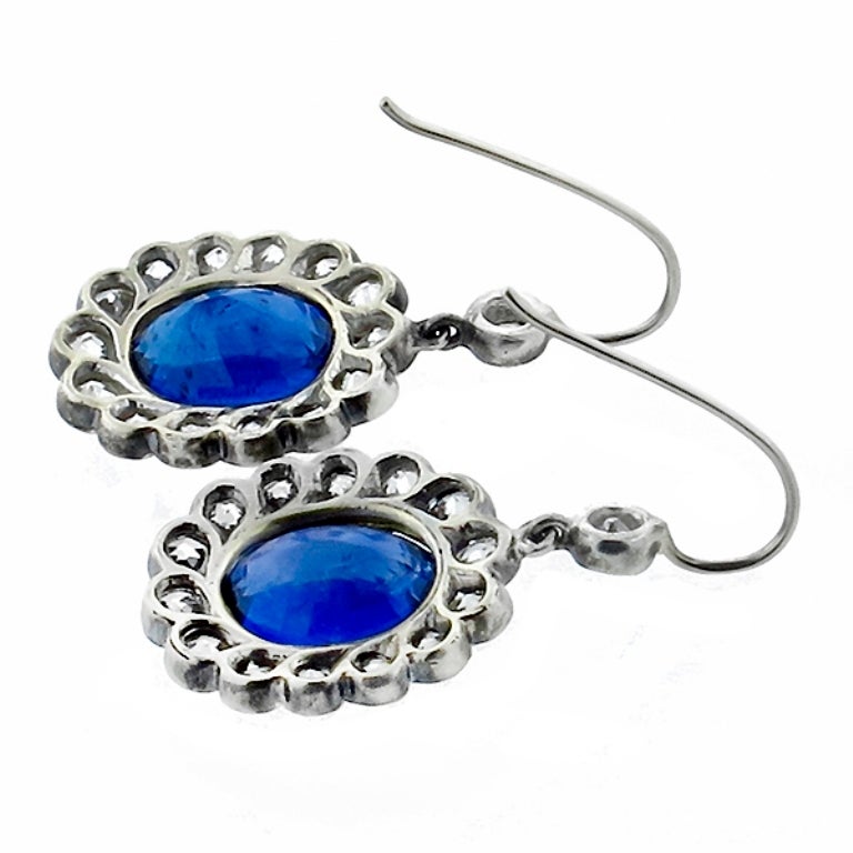 This beautiful antique pair of silver & 14k yellow gold earrings, feature 2 oval cut sapphires that weigh 8.32ct. The sapphires are adorned with approximately 2.80ct of old mine cut diamonds graded H color with VS clarity. The earrings measure 31mm
