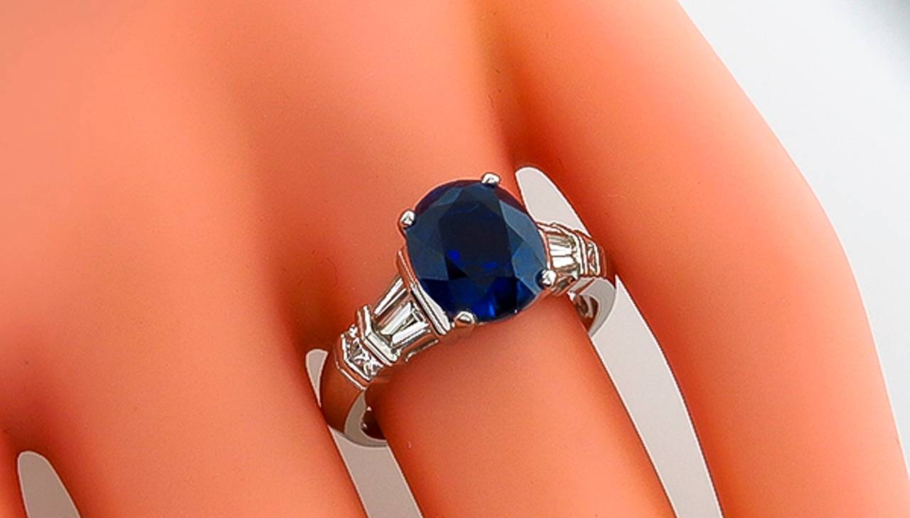 This gorgeous platinum ring is centered with a vivid blue oval cut GIA certified no heat sapphire that weighs 3.08ct. The center stone is accentuated by sparkling baguette and princess cut diamonds that weigh approximately 0.50ct. The color of these