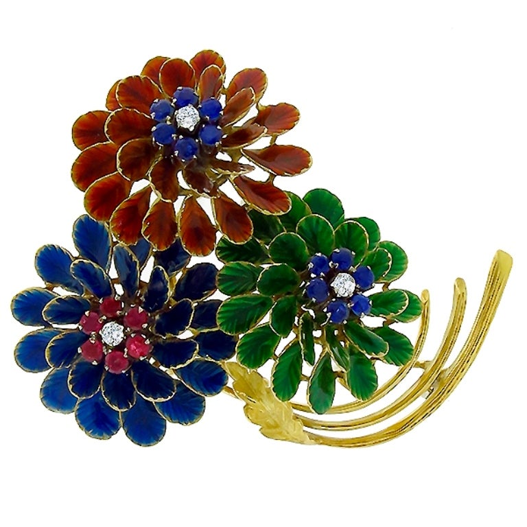 This lovely pin from the 1960s, is adorned with green, red- orange and blue enamel inlays. The enamel is accentuated by round cut ruby, sapphire and diamonds that weigh approximately 0.15ct, 0.30ct and 0.50ct respectively. The color of the diamonds