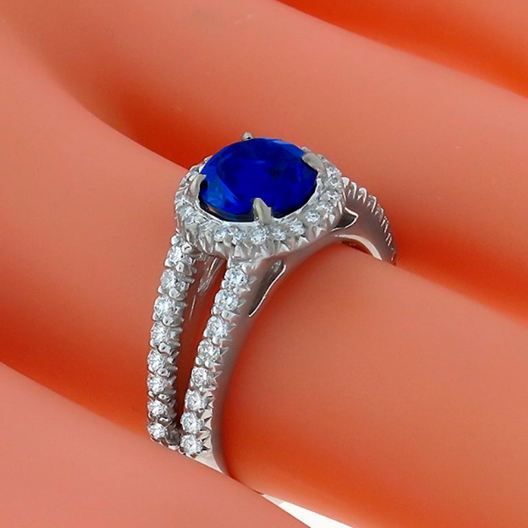 Made of 18k white gold, this ring centers a vivid blue round cut Ceylon sapphire that weighs 2.08ct. The center stone is accentuated by round cut diamonds weighing approximately 1.15ct. The ring is size 6 1/4, and can be resized. 
It is signed