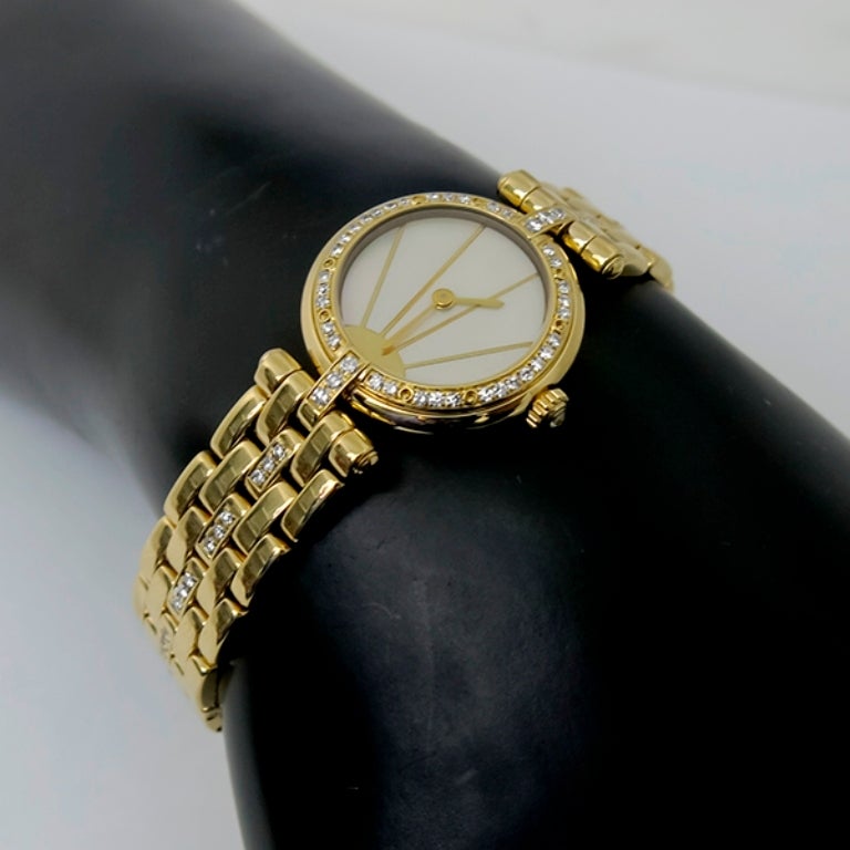 This beautiful Cartier watch has a white mother-of-pearl dial with gold sun-ray frame and gold hour markers. The watch is set with round cut diamonds weighing approximately 1.00ct. and is signed Cartier Quartz Swiss Made 18K. It will fit a standard