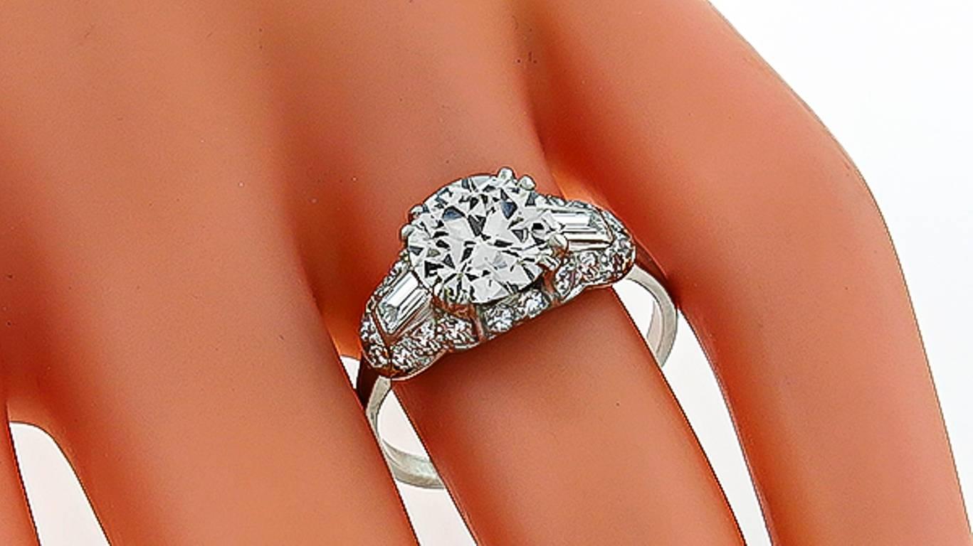 This amazing platinum ring centers a sparkling GIA certified round brilliant cut diamond that weighs 2.05ct. and is graded J color with VVS2 clarity. The center stone is accentuated by dazzling baguette and round cut diamonds weighing approximately