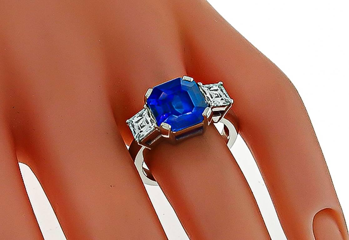 This beautiful platinum ring centers a natural vivid blue asscher cut sapphire that weighs 6.49ct. The center stone is flanked by two sparkling french cut diamonds that weigh approximately 1.60ct. graded F-G color with VS1 clarity. The ring is