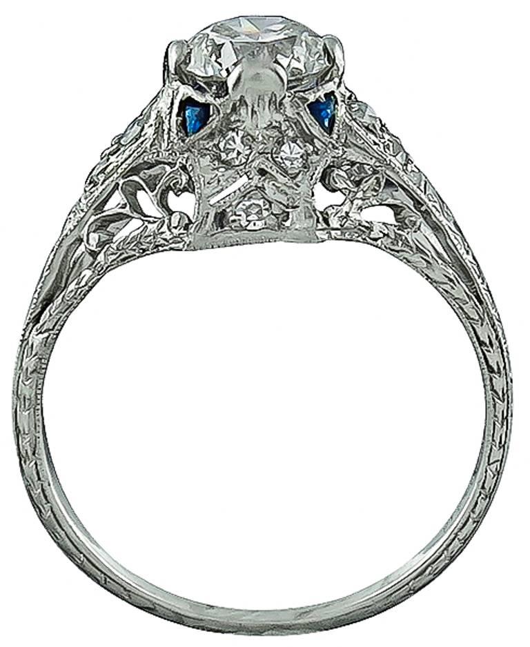 This stunning platinum ring  is centered with a sparkling GIA certified round brilliant cut diamond that weighs 0.96ct. The color of the diamond is I with SI1 clarity. The center diamond is accentuated by sapphire and diamond accents. The ring has
