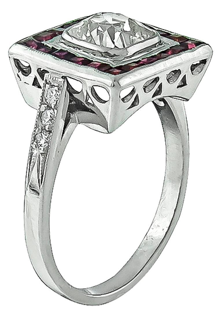 This amazing platinum ring from the Art Deco era is centered with a sparkling old mine cushion cut diamond that weighs 1.15ct. and is graded K color with VS2 clarity. The center stone is accentuated by bright red square cut rubies and sparkling
