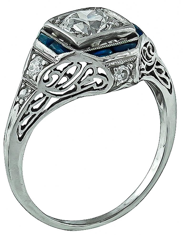 Handcrafted from the from the Art Deco era, this ring is centered with a sparkling old European cut diamond that weighs 0.70ct. graded F color with VS1 clarity. The center stone is accentuated by diamond and sapphire accents.
The ring is currently