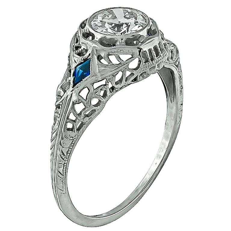 This magnificent 18k white gold engagement ring from the Art Deco era, is centered with a sparkling GIA certified round brilliant cut diamond that weighs 0.63ct. graded G color with VS2 clarity. The center diamond is flanked by kite cut sapphire