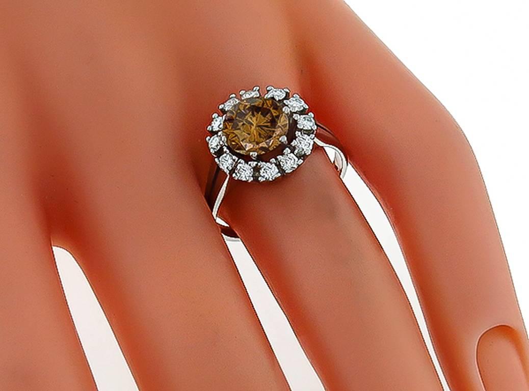 Réalisée en or blanc 18 carats, cette bague est centrée d'un superbe diamant de couleur naturelle brun orangé de 2,20 carats, de pureté SI3. La pierre centrale est rehaussée de diamants ronds pesant environ 0,45 ct. de couleur G et de pureté VS.
La